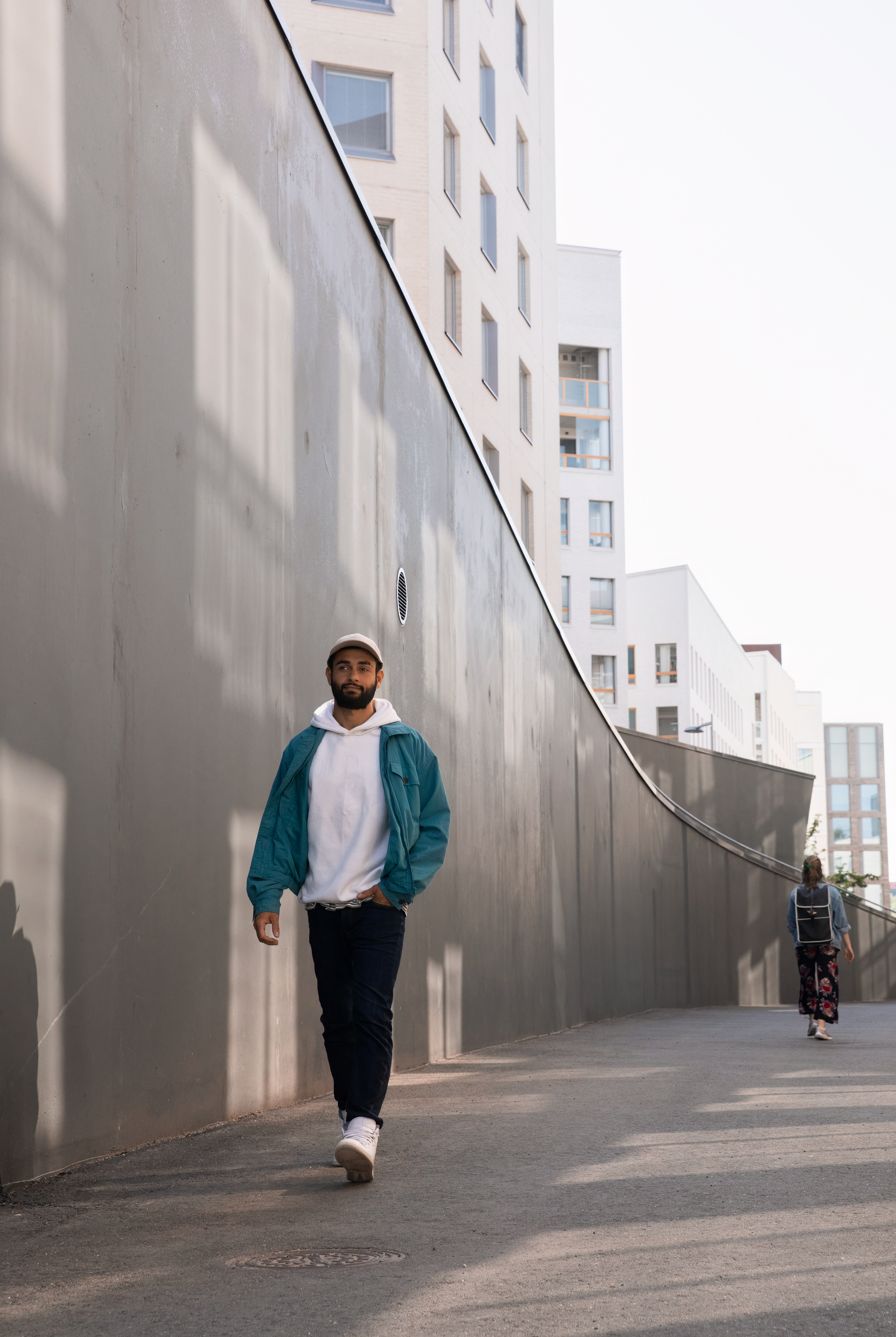 Man walking outside next to a concrete wall